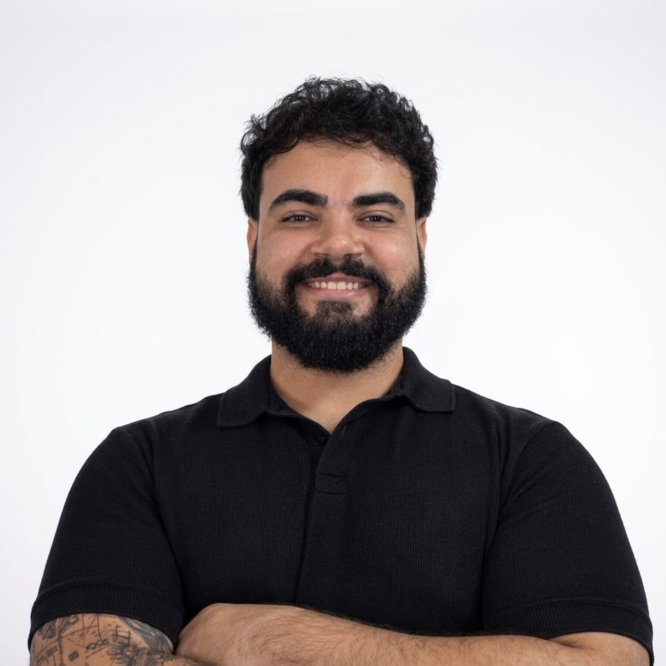 Yuri Barbosa, de camisa polo preta e braços cruzados, sorrindo para a câmera